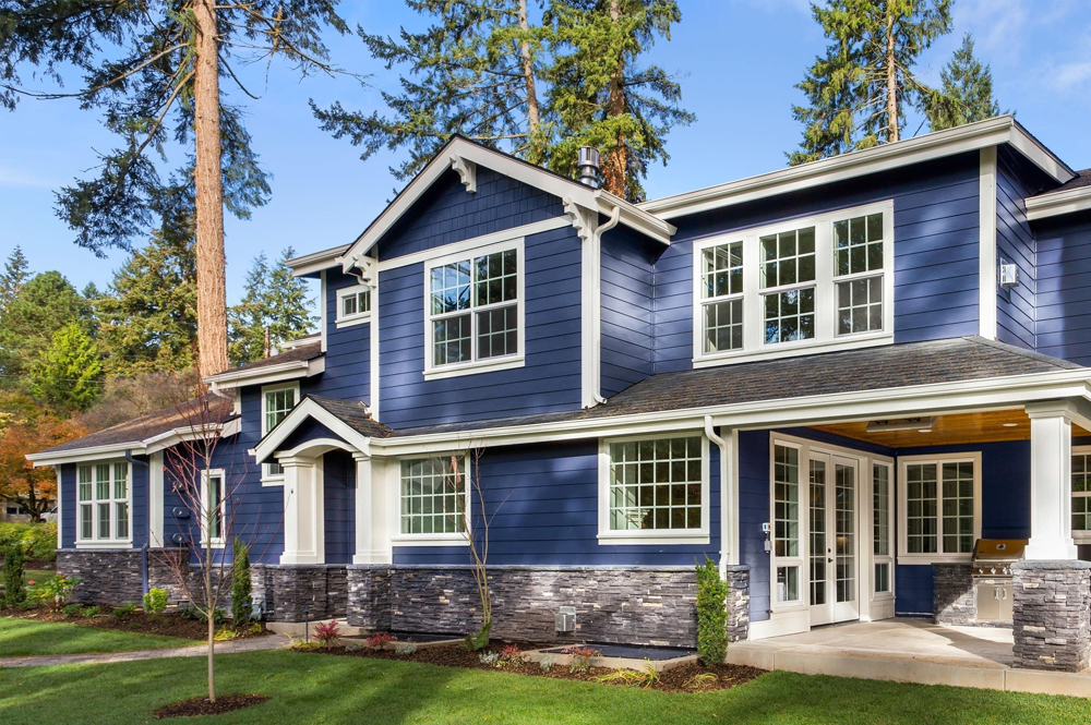 Modern blue house showcasing large white-framed windows.